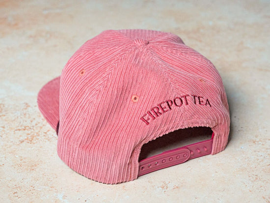 back of pink corduroy hat that says "firepot tea"