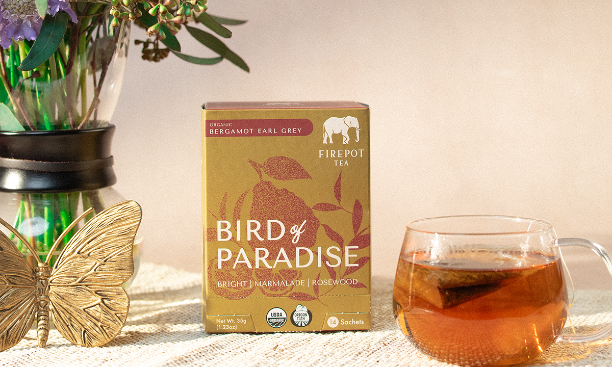 Bird of Paradise tea box with a cup of tea and flowers on a table