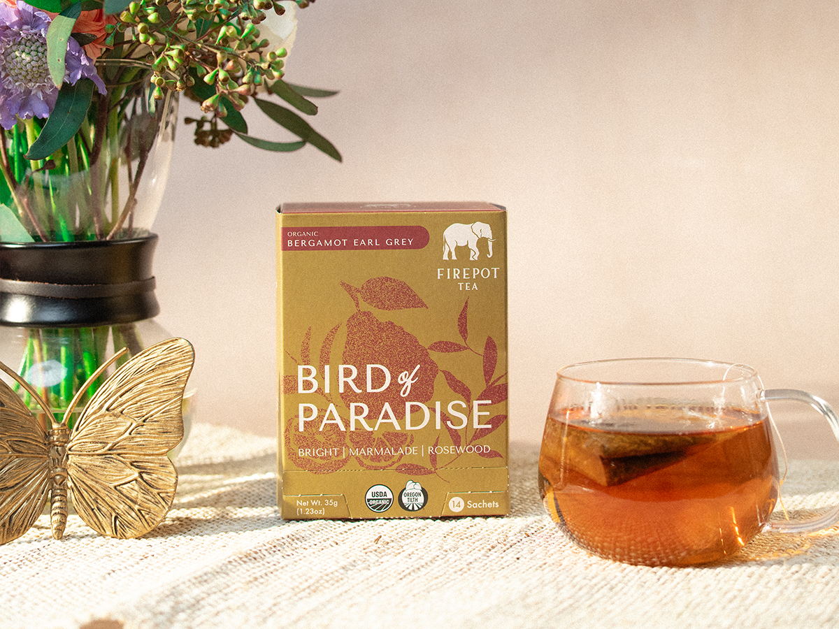 Bird of Paradise tea box with a cup of tea and flowers on a table