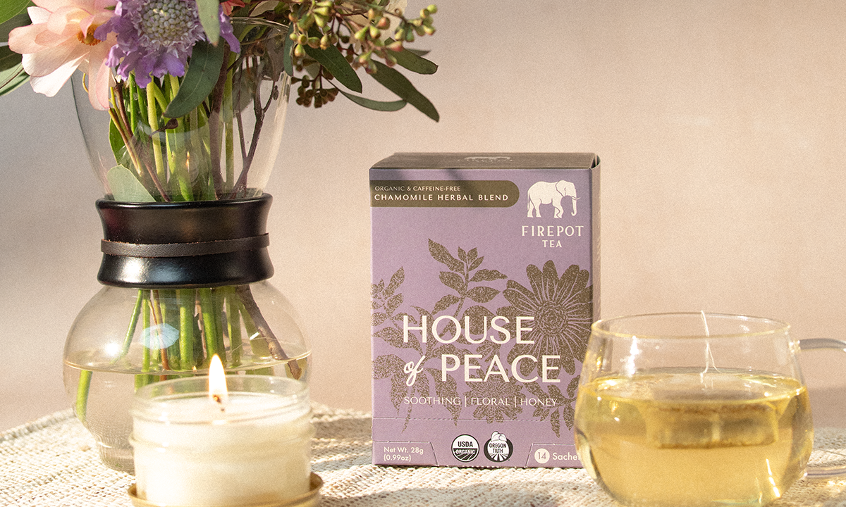 Tea packaging labeled 'House of Peace' with a candle and glass of tea on a table.