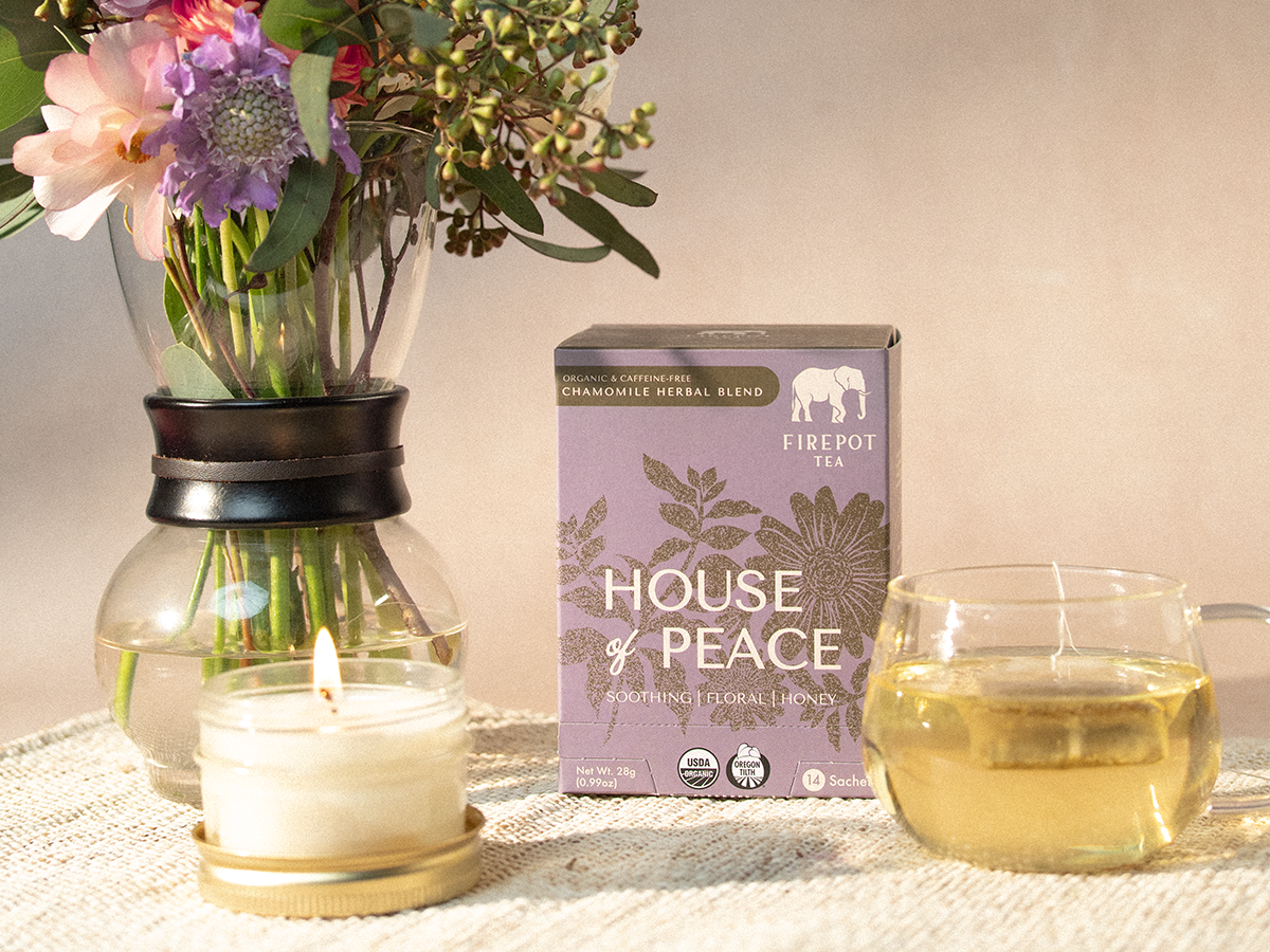Tea packaging labeled 'House of Peace' with a candle and glass of tea on a table.