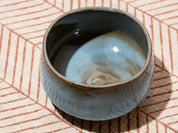 Ceramic cup with a textured surface on a patterned fabric background