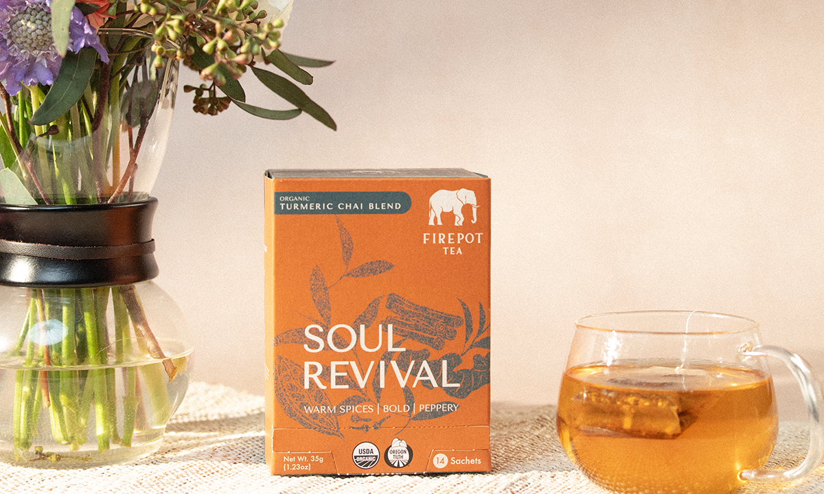 Firepot Tea 'Soul Revival' box with a glass of tea and flowers on a table.