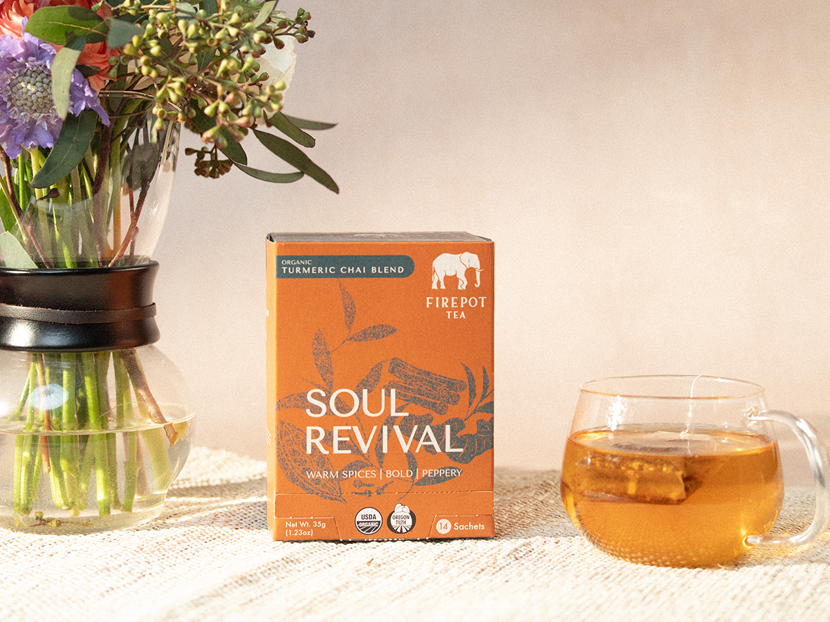 Firepot Tea 'Soul Revival' box with a glass of tea and flowers on a table.