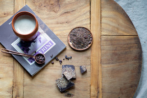 Firepot loose leaf Chocolate Chai next to a bar of chocolate and a chai latte on a book