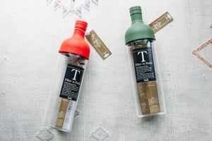 red and green Hario Filter-in Bottle Cold Brewed Tea bottles on a white Moroccan blanket