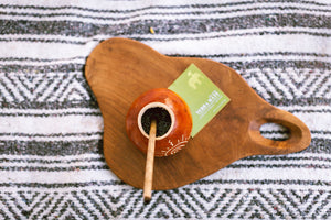 overhead of mate gourd with bamboo straw with yerba mate steeping in the gourd, on a wooden board